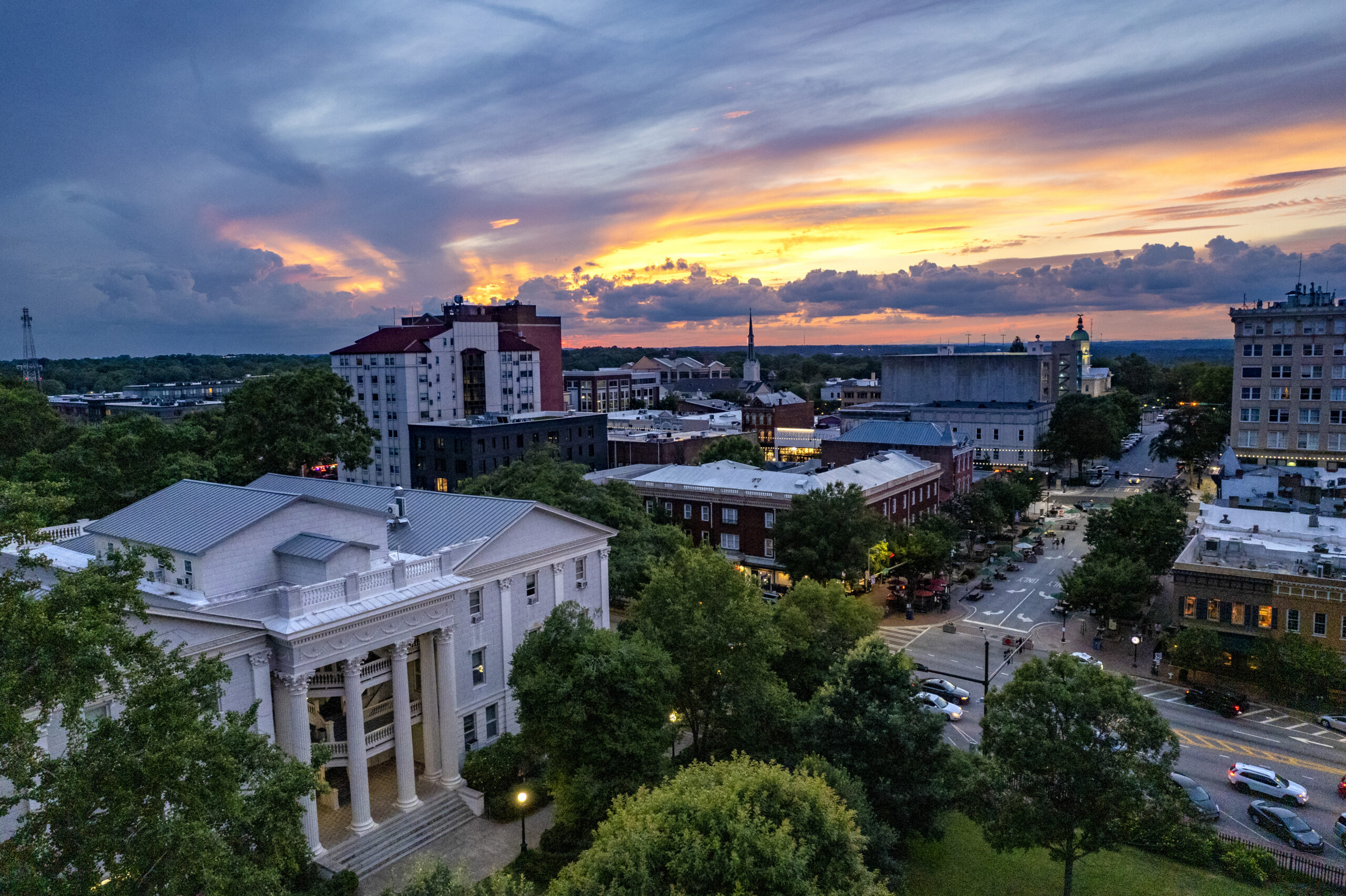 A city with trees and buildings at sunset.